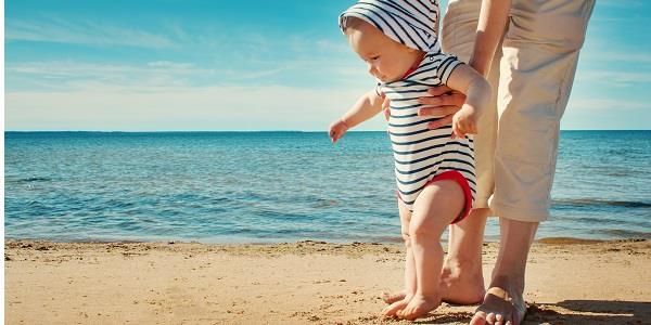 Cute baby taking steps on the beach.